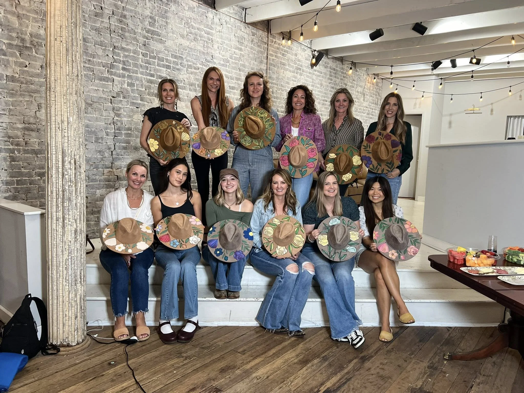 A group posing with their finished round canvases after a celebration session