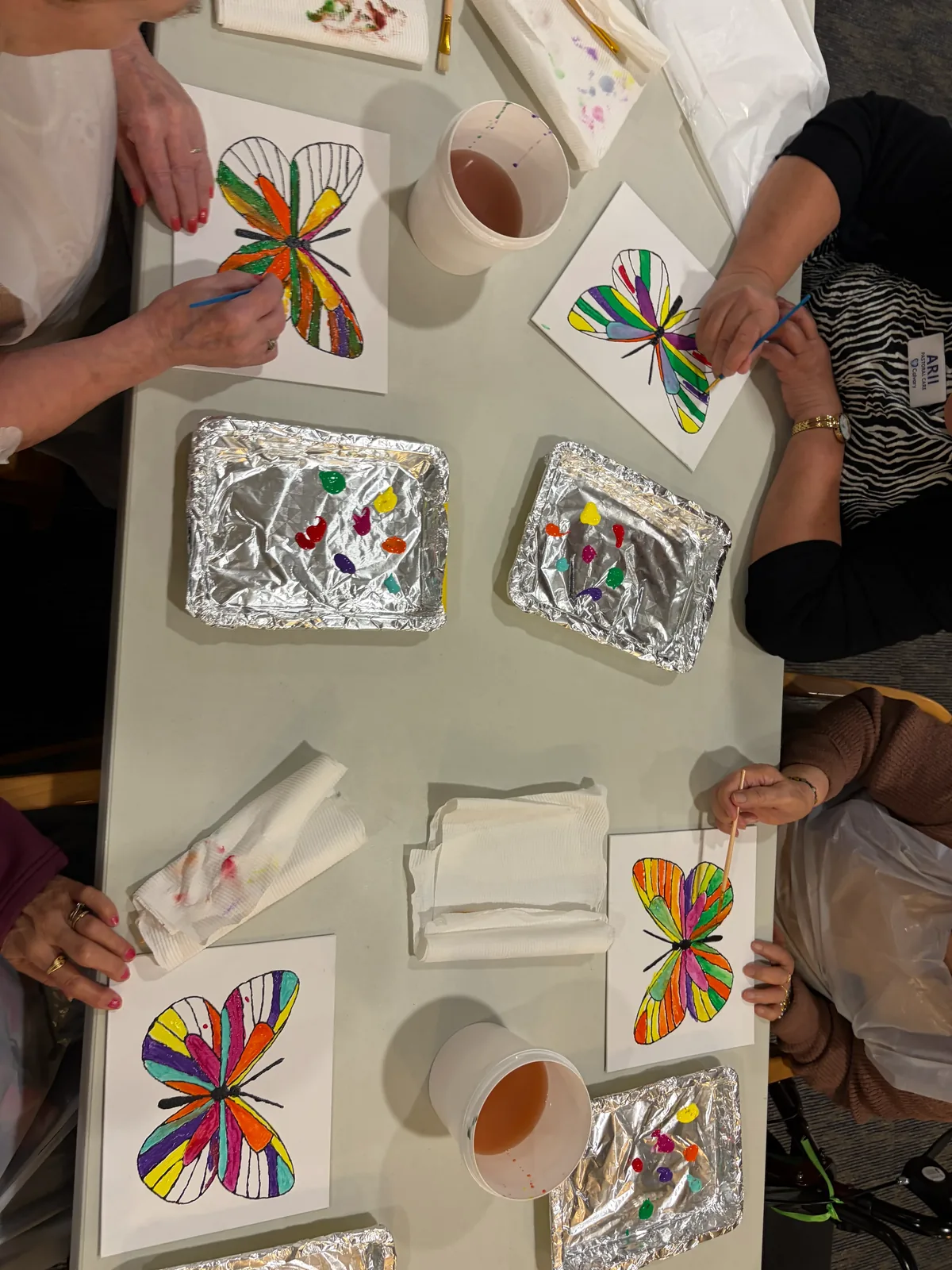 A group painting butterfly canvases together at a mobile art workshop