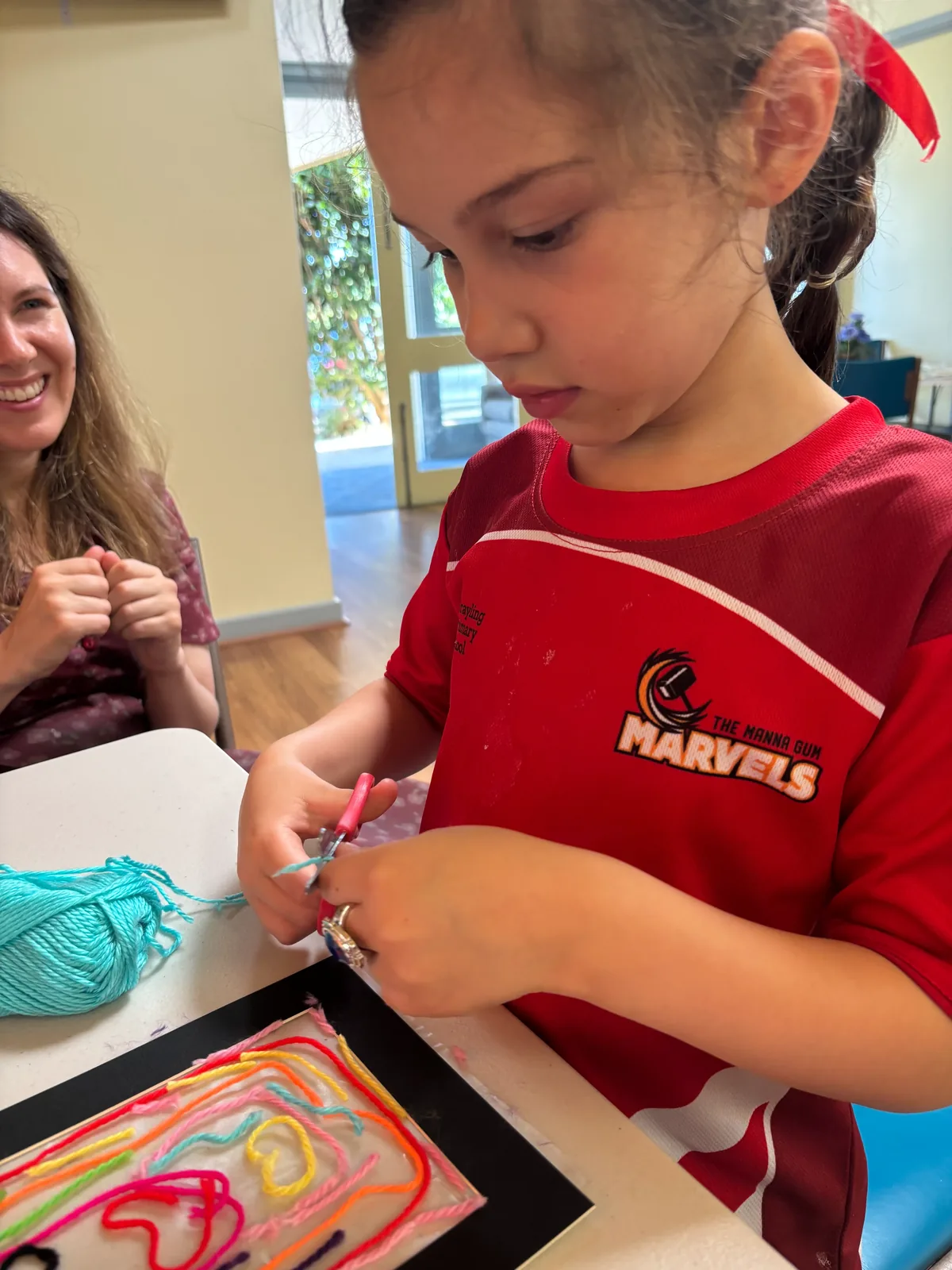 A child concentrating on painting their own colourful artwork at a kids art and craft workshop