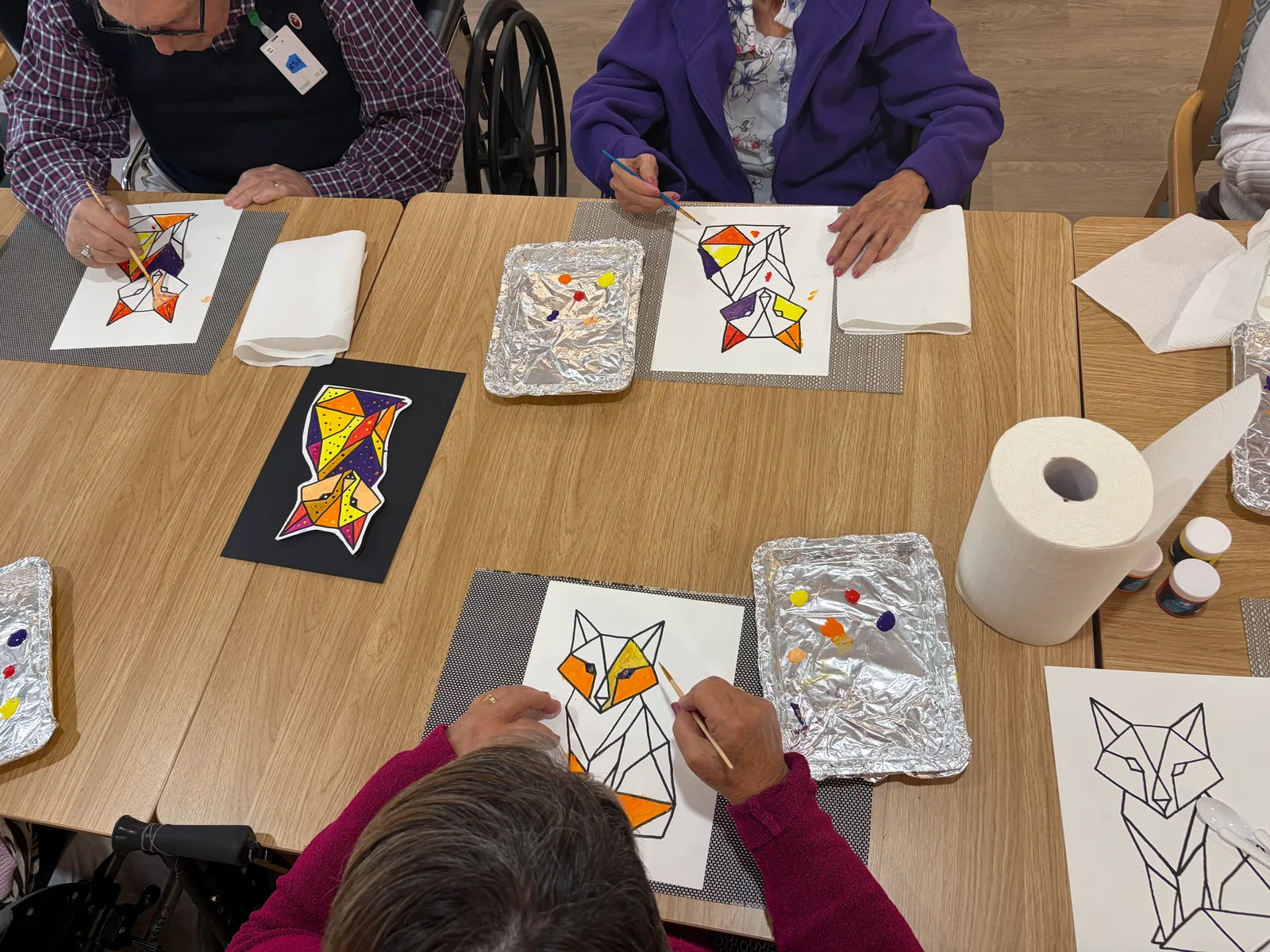 Aged care residents painting canvases together at a mobile art workshop brought to their facility