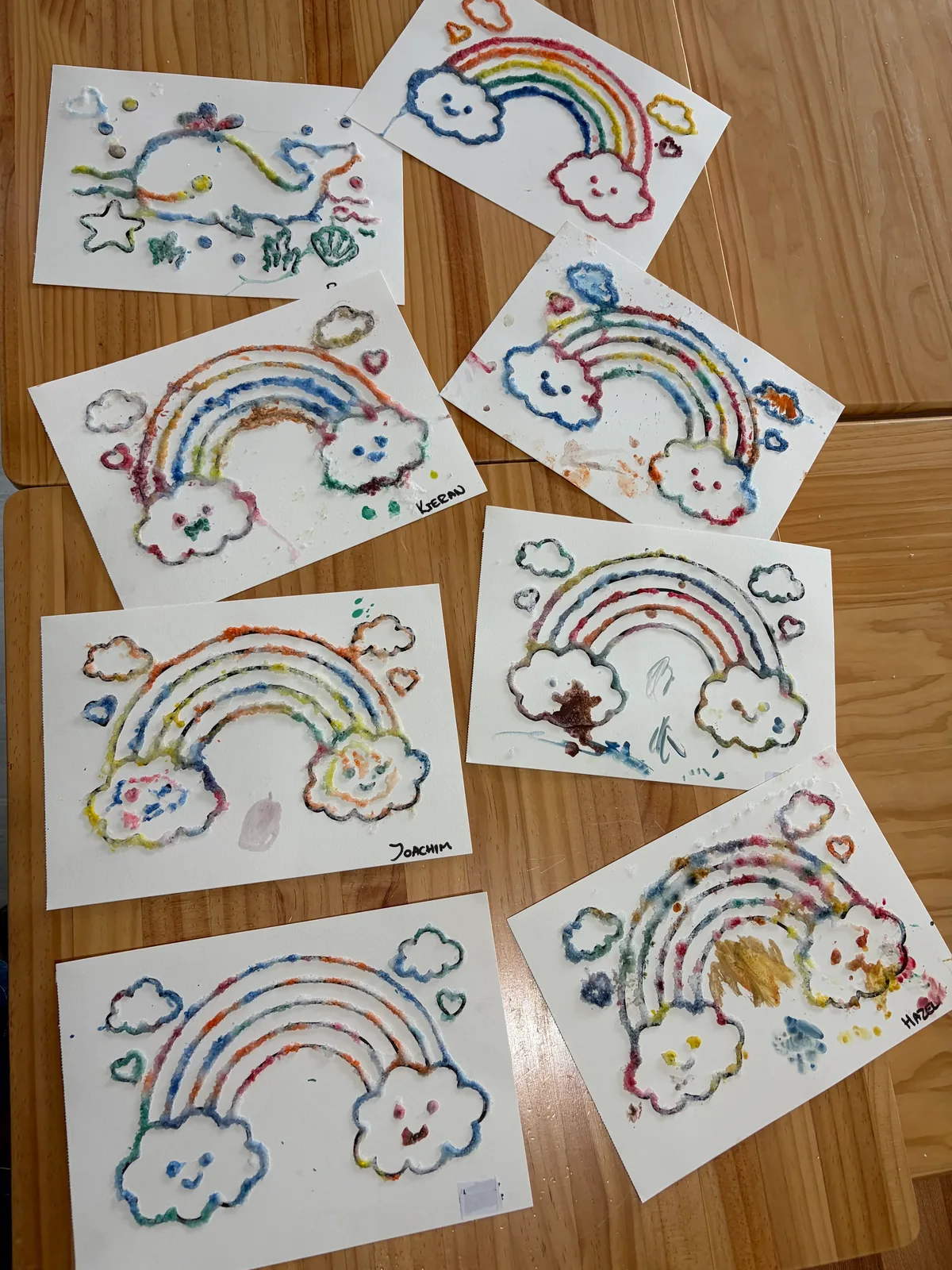 A collection of rainbow salt art pieces created by children in an art and craft session