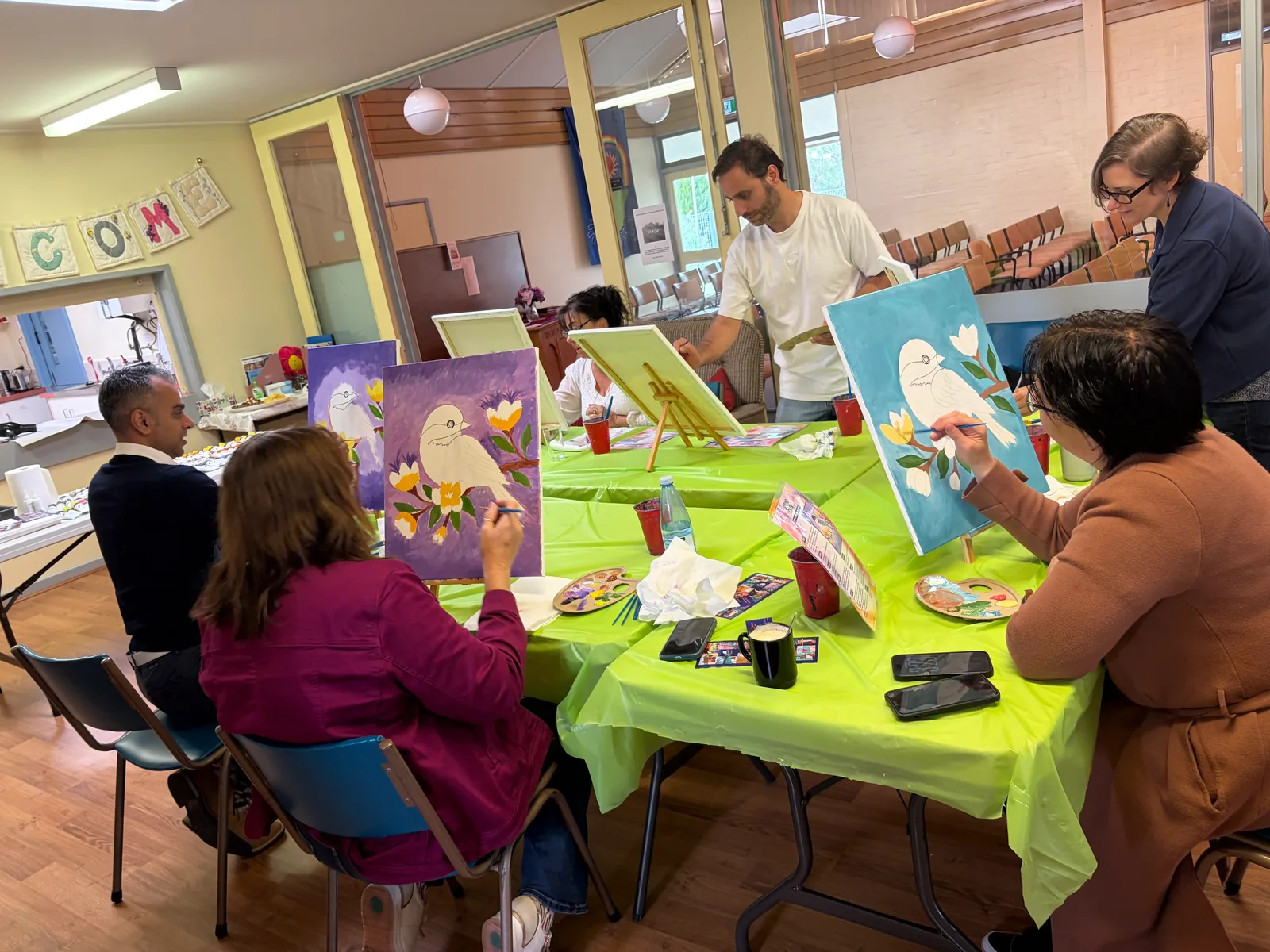 Adults painting canvases side by side at a Bluey's Imaginations creative painting party